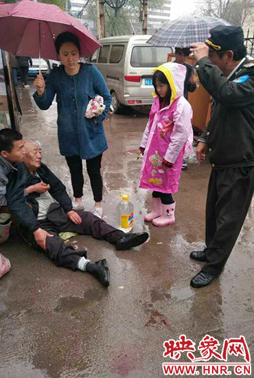 女孩為倒地老人撐傘。