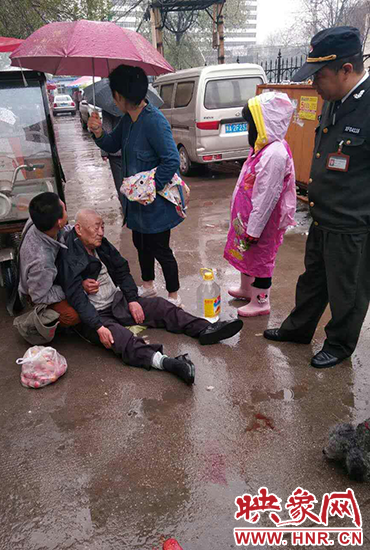 女孩為倒地老人撐傘。