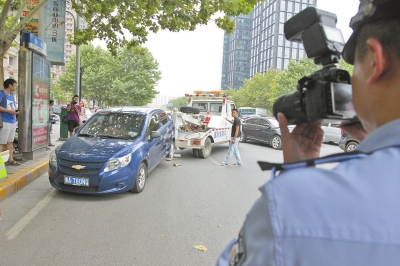 在金水路，交警對(duì)在機(jī)動(dòng)車道違法停放的車輛施行拖離