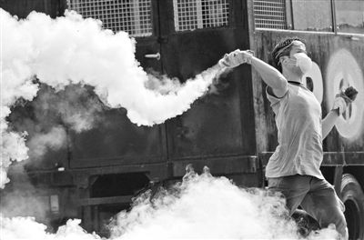 12月2日，泰國(guó)曼谷，一名反政府示威者在總理府附近向負(fù)責(zé)執(zhí)勤的警察投擲催淚彈。英拉請(qǐng)求示威者不要再試圖占領(lǐng)政府工作部門，不要逼迫政府工作人員選邊站。