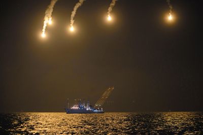 22日，搜救人員在照明彈的光亮下連夜搜救。