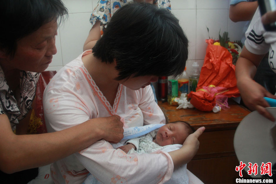 圖為久別重逢，獲救嬰兒母親悉心撫摸愛子。張一辰 攝