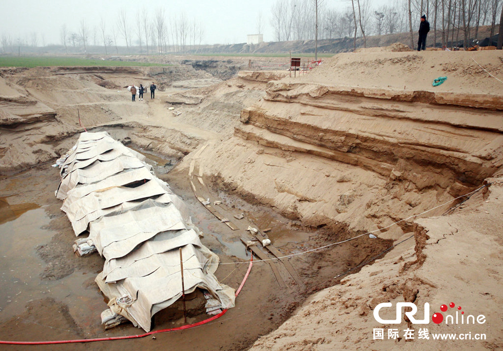 2014年1月6日，河南洛陽古沉船發(fā)掘現(xiàn)場，近日有雨雪天，考古人員給古沉船披上一層“雨衣”。