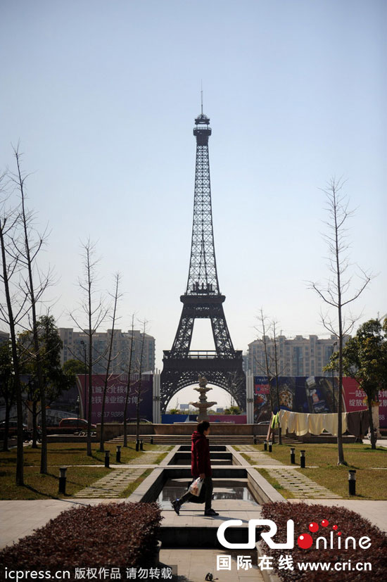 　2014年3月21日，杭州天都城，農(nóng)民在山寨埃菲爾鐵塔下耕作。圖片來源：東方IC