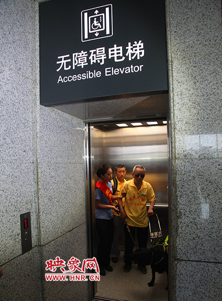 視力殘障人士在工作人員引導(dǎo)下乘坐無障礙電梯