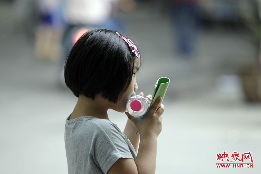 6月7日，鄭州回中考點(diǎn)，一名孩子拿著一瓶礦泉水，等待哥哥走出考場(chǎng)