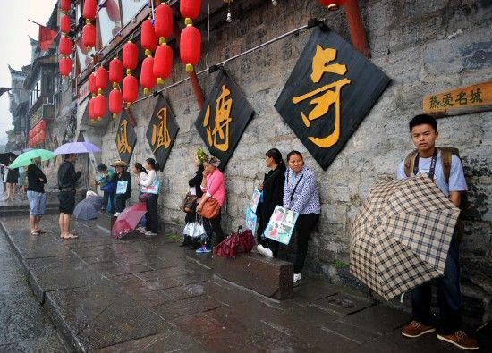 　4月29日上午11時20分，一些游客和古城當?shù)氐木用穸阍谝粋€酒吧的屋檐下避雨。這些當?shù)鼐用褚詾橛慰团恼罩\生，一場降雨讓他們的生意更加清淡。