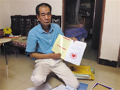 翻出一家網(wǎng)站贈(zèng)予的“中國(guó)好人”證書，區(qū)少坤單膝跪在地上，“你看，我是中國(guó)好人啊。” 范春旭 攝