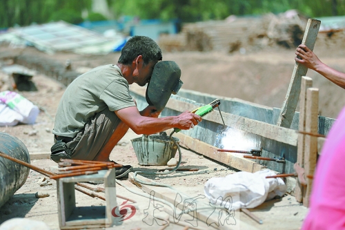 　正午陽光下，工地上的焊接工人還在認(rèn)真工作。