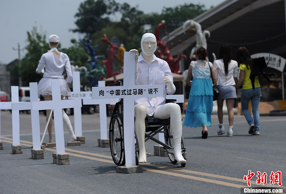 4月16日，重慶市洋人街上擺放著兩個(gè)受了傷的塑料人像“模特”，旁邊十字架上寫(xiě)著向“中國(guó)式過(guò)馬路”說(shuō)不