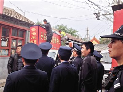 昨日下午,東城區(qū)工商、城管、公安等部門,對雍和宮附近的預(yù)測中心進(jìn)行清理整頓,站在車頂?shù)膬擅と苏鸪患摇邦A(yù)測中心”的招牌。因雍和宮、白云觀等文化景點外聚集大量算命先生,被媒體稱為“算命一條街”。本版攝影/新京報記者 李寧 攝