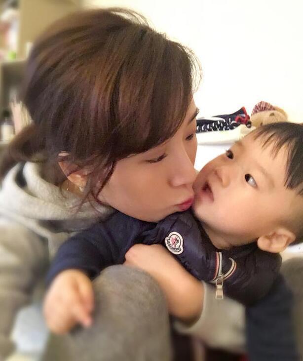 照片中李念狂吻兒子，小寶貝自顧自地玩著。