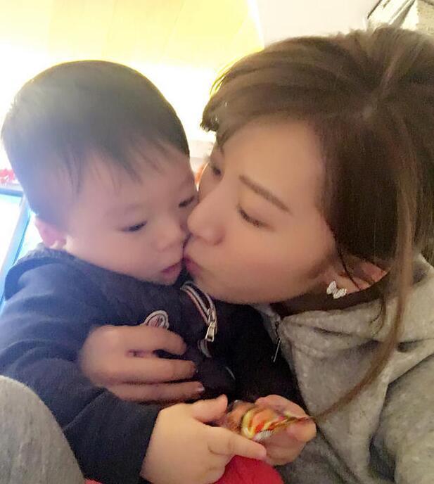 照片中李念狂吻兒子，小寶貝自顧自地玩著。