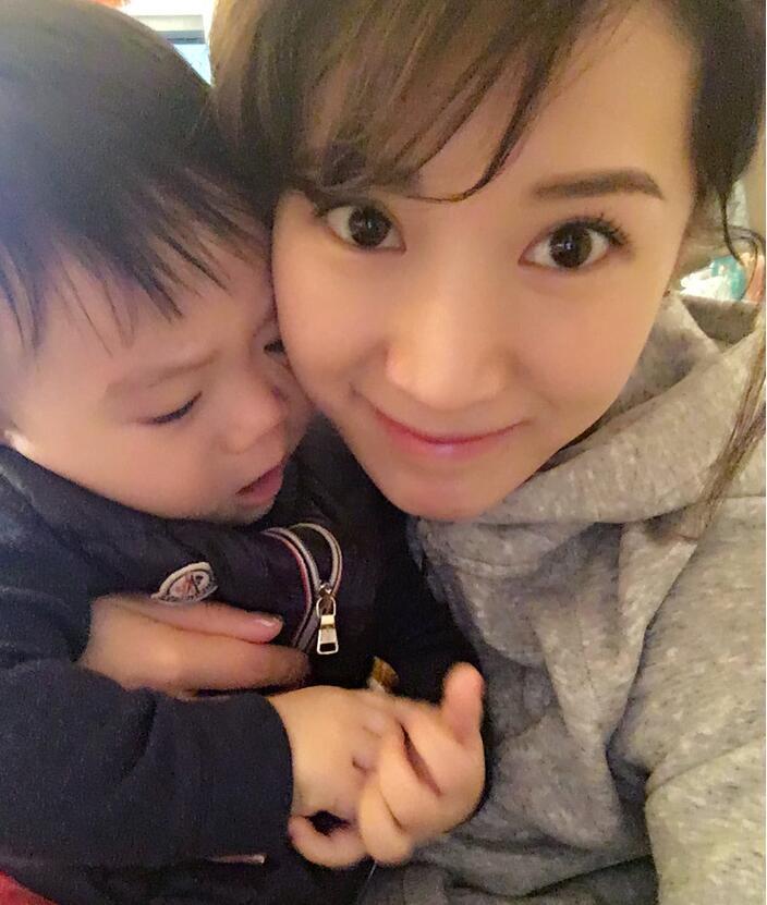 照片中李念狂吻兒子，小寶貝自顧自地玩著。