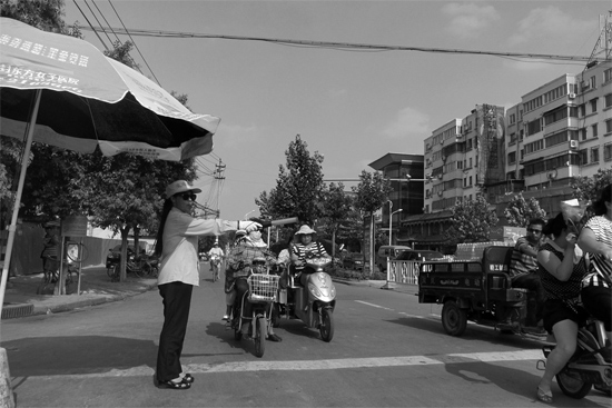 昨日，開封市區(qū)一名協(xié)管員在指揮群眾過馬路