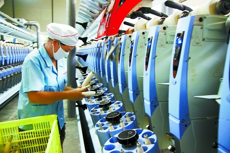 7月3日，在鄧州市永泰棉紡有限公司電腦控制全自動紡紗車間，紡織工人正在生產棉紗。