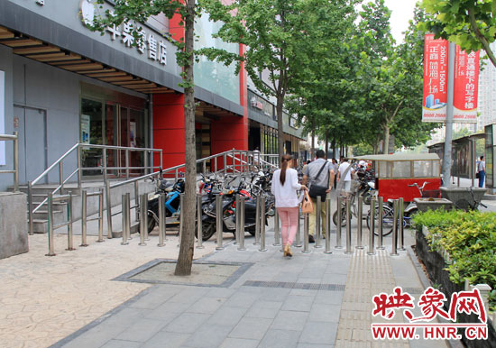 圖中道路左側的無障礙通道被鋼管隔離,右側的盲道也被侵占。