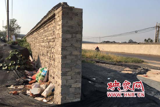 一墻之隔，一邊是道路，一邊是垃圾和荒草，市民質(zhì)疑其為遮羞墻。