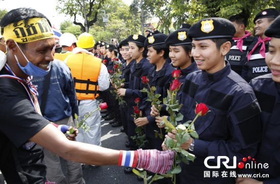 2013年12月03日,曼谷總理府與曼谷警署允許反政府示威民眾進入,雙方進入暫時“停戰(zhàn)”狀態(tài)迎接泰王生日。曼谷警察總署,女警們手持鮮花送給反政府示威民眾。圖片來源:Manish Swarup/東方IC