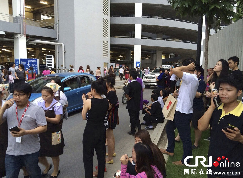 當(dāng)?shù)貢r(shí)間2014年5月5日，泰國(guó)清萊，工人們站在一棟大樓外避難。