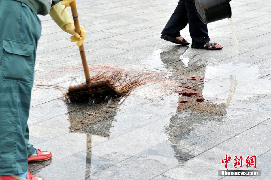 圖為環(huán)衛(wèi)工人在清理案發(fā)地點的血跡。