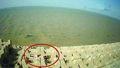 孫正龍游上岸，趴在海邊精疲力盡。