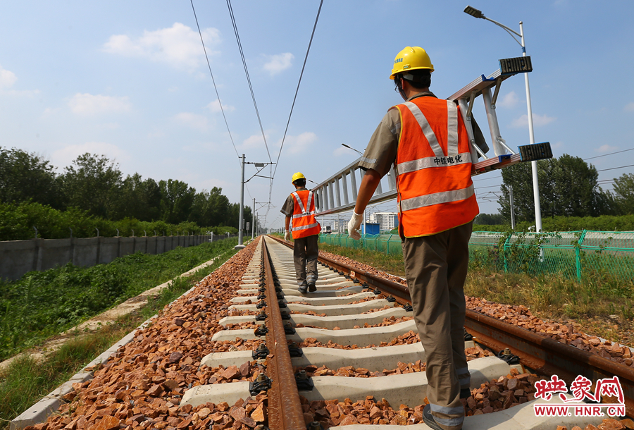 滾燙的鐵軌上，兩個扛著梯子的檢修員走向第四個檢修點