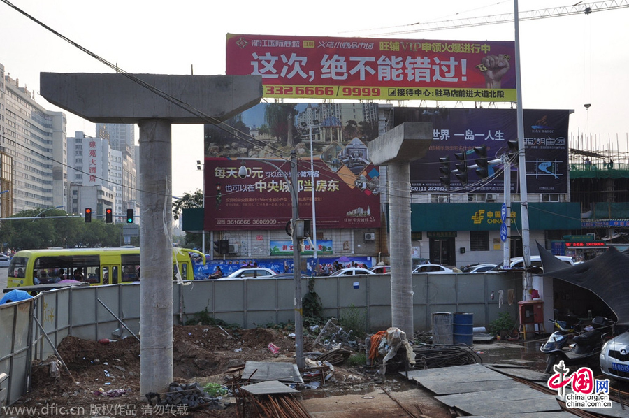 過街天橋一側(cè)的橋樁早已打好,可是對面的郵政銀行網(wǎng)點依舊在照常營業(yè)。