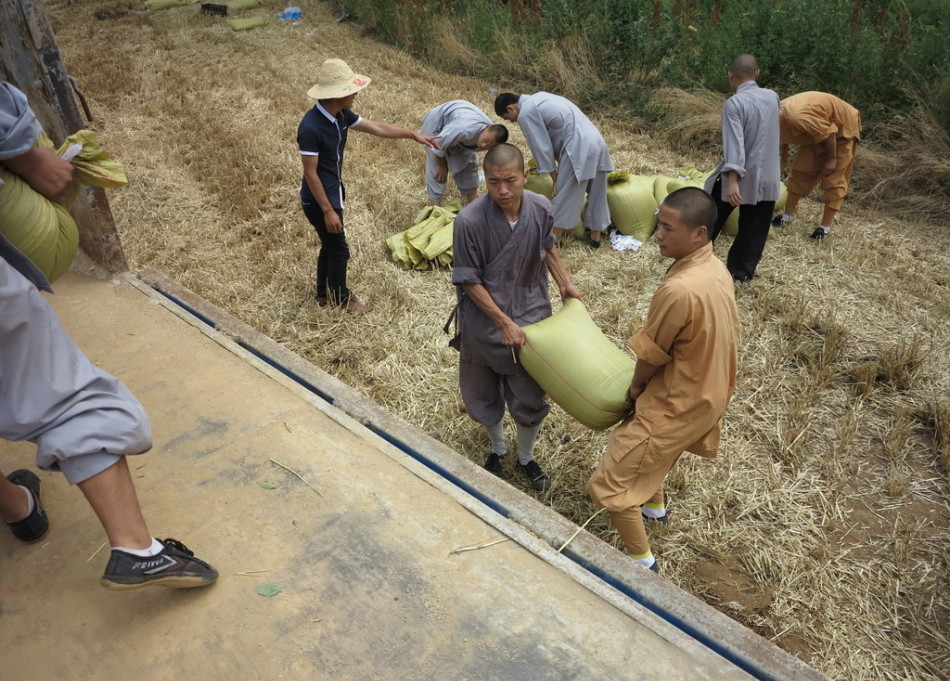 武僧將打包后的糧食集中至運輸車輛上。