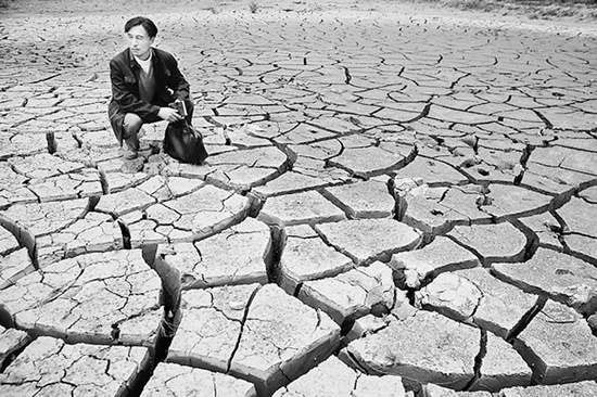 蹲在干涸的田地里，焦裕祿為饑餓的百姓揪心不已 《焦裕祿》劇照